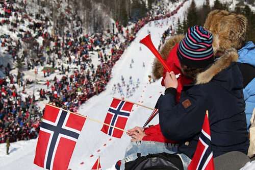 Feltet i 5-mila under VM i Holmenkollen i 2011 er nede i bakken, tett omkranset av stort publikum og norske flagg. Foto: Hemmersbach/NordicFocus. Feltet i 5-mila under VM i Holmenkollen i 2011 er nede i bakken, tett omkranset av stort publikum og norske flagg. Foto: Hemmersbach/NordicFocus.