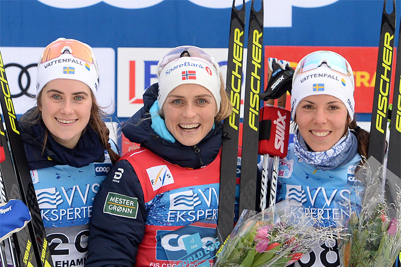 Damepallen under verdenscupens 10 km i fri teknikk på Lillehammer i 2018. Fra venstre: Ebba Andersson (2. plass), Therese Johaug (1) og Charlotte Kalla (3). Foto: Tumashov/NordicFocus. Damepallen under verdenscupens 10 km i fri teknikk på Lillehammer i 2018. Fra venstre: Ebba Andersson (2. plass), Therese Johaug (1) og Charlotte Kalla (3). Foto: Tumashov/NordicFocus.