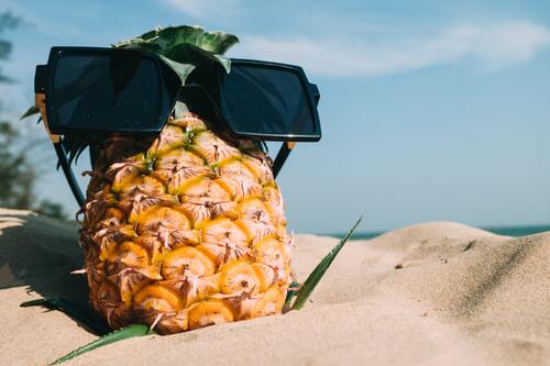 Ananas på strand med solbriller på