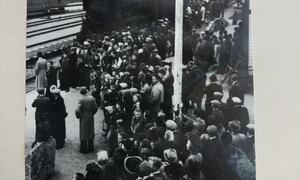 Bildet viser toget som ruller inn på Jevnaker stasjon og folk er samlet på perrongen. 8. mai 1945.