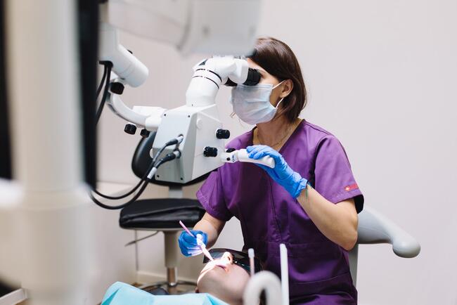 Bildet viser en tannlege og en pasient som sitter i en tannlegestol.