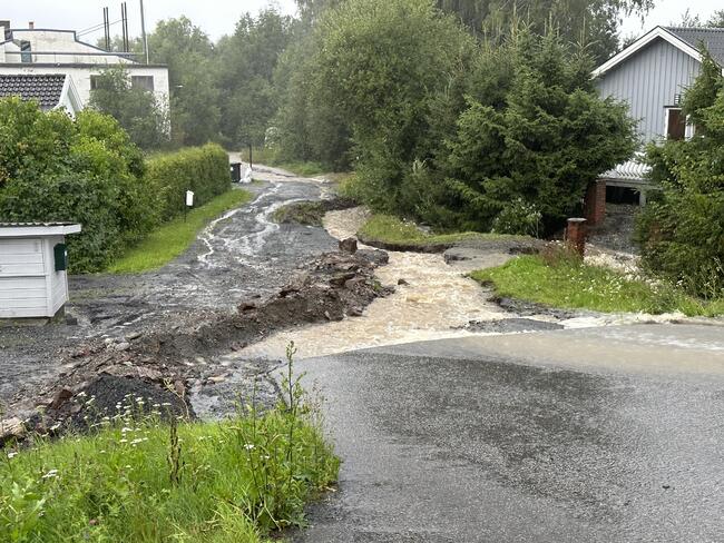 Bildet viser en vei ødelagt av store vannmasser.