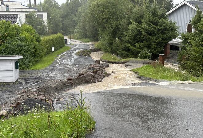 Bildet viser en vei ødelagt av store vannmasser.
