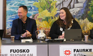 En kvinne og en mann smiler. Kvinnen har ordførerkjedet på seg. Sitter bak et bord det står Fauske kommune på.