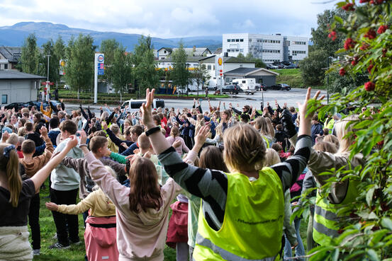 Stor gruppe med barn i en park danser med hendene i været