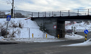 Bildet viser en vei i forkant, og en togbro over veien. Det er satt opp anleggsgjerder der det tidligere har vært en bussholdeplass.