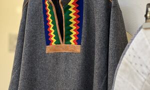Grå samisk kofte med grønn, gul, rød og blå krage på en henger
