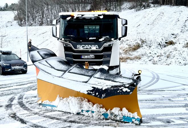 Lastebil med brøyteplog står parkert i snøen