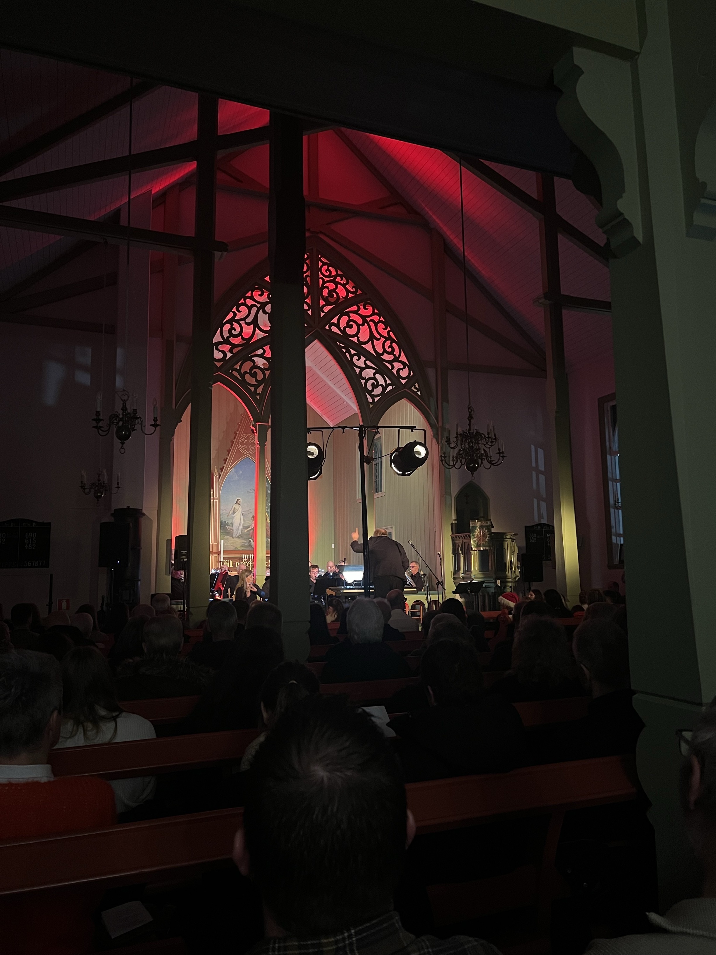 Konsert i en kirke. Dirigent med kor i bakgrunn