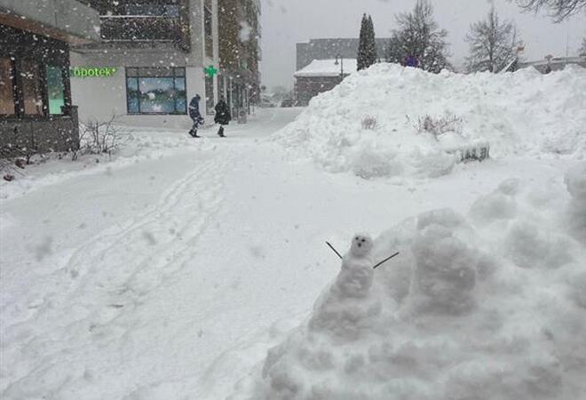 Bildet viser mye snø på bakken, i lufta og en liten snømann.