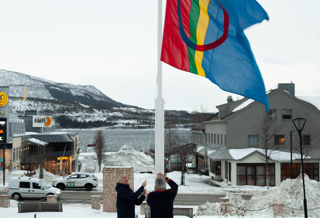 to menn heiser samisk flagg på flaggstang.