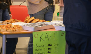 Bord med bakverk og en plakat med Kafe og priser.