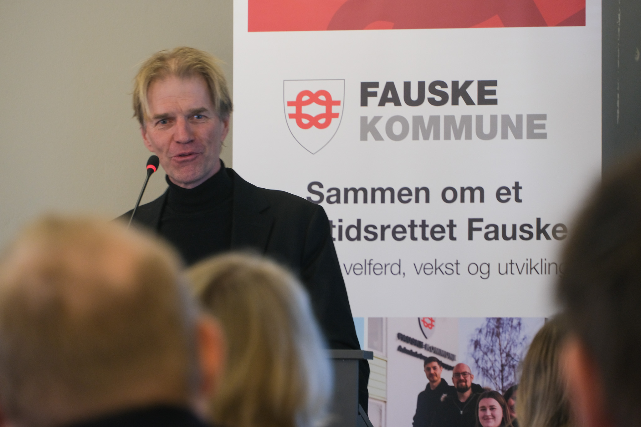 Mann står ved en talerstol og snakket til en forsamling