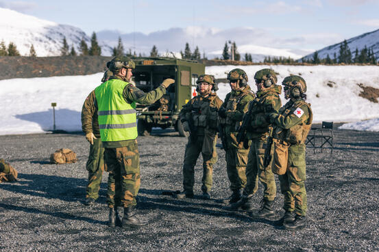 Menn i militæruniform står ute og får instruksjoner
