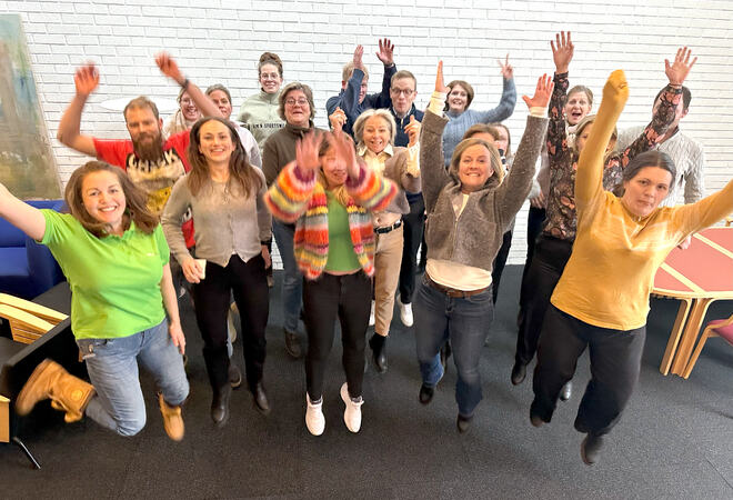 Bildet viser en stor gruppe personer som hopper med armene i været og store smil.