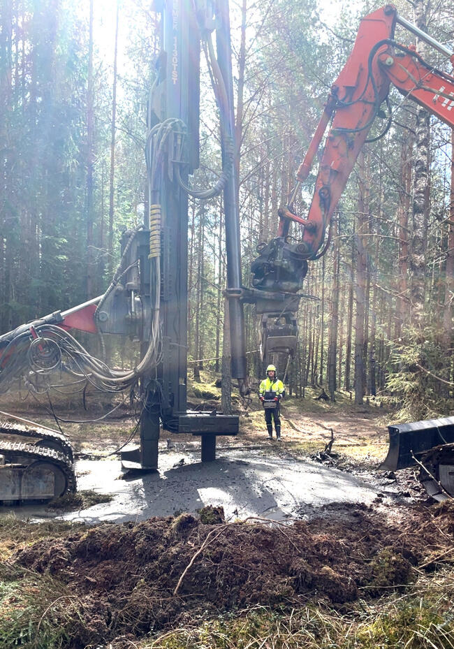 Bildet viser tungt maskinelt utstyr i en skog. Midt på bildet er en person.