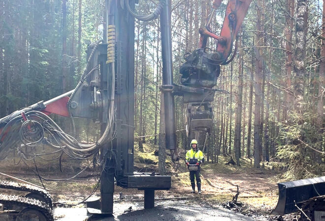 Bildet viser tungt maskinelt utstyr i en skog. Midt på bildet er en person.