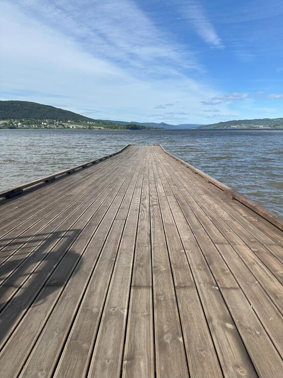 Bildet viser ei trebrygge, med Randsfjorden på tre kanter. Det er nesten blå himmel.
