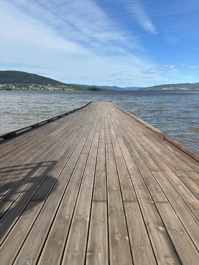 Bildet viser ei trebrygge, med Randsfjorden på tre kanter. Det er nesten blå himmel.