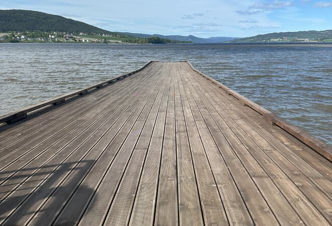 Bildet viser ei trebrygge, med Randsfjorden på tre kanter. Det er nesten blå himmel.