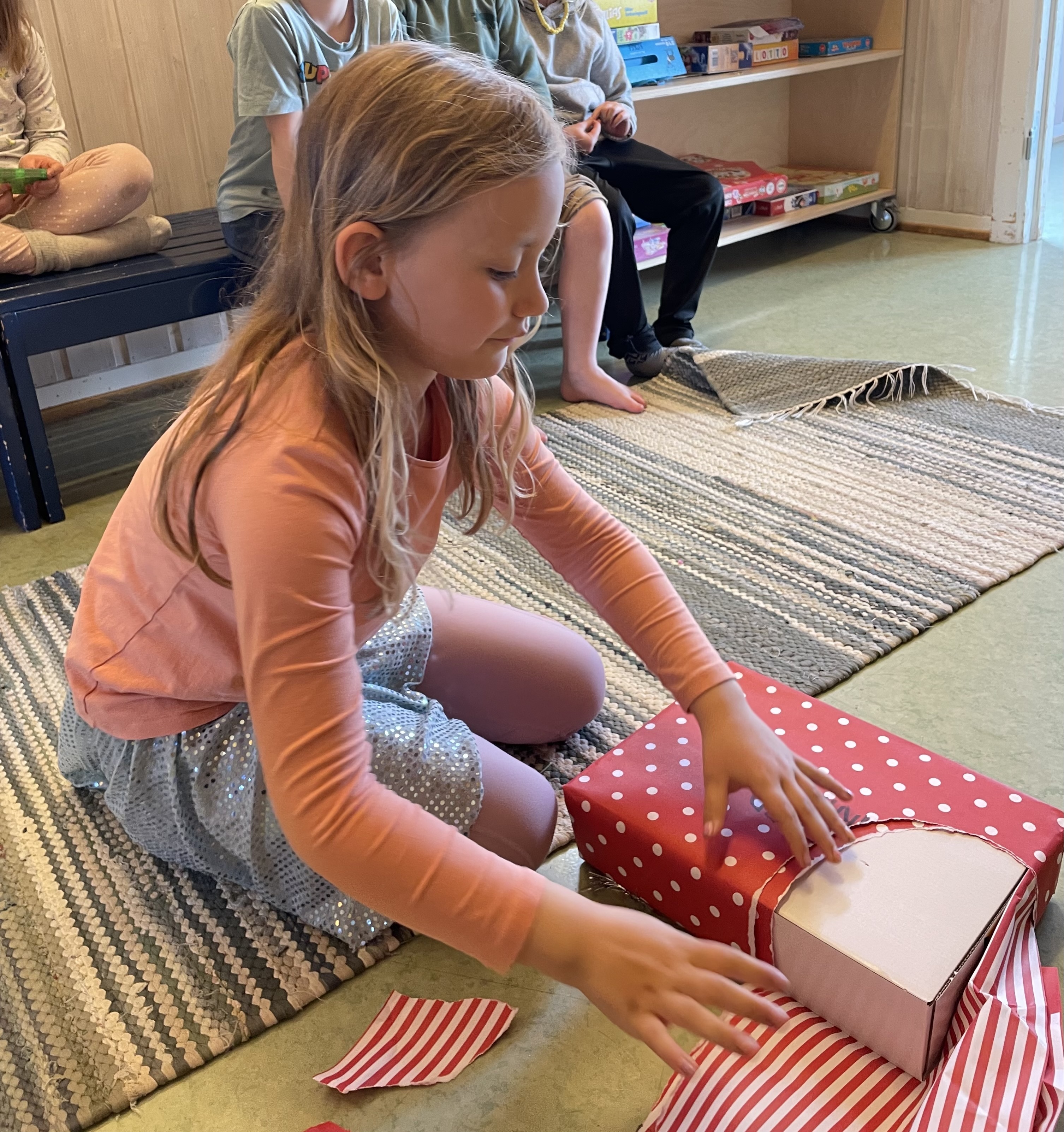 Jente åpner en pakke innpakket i gavepapir